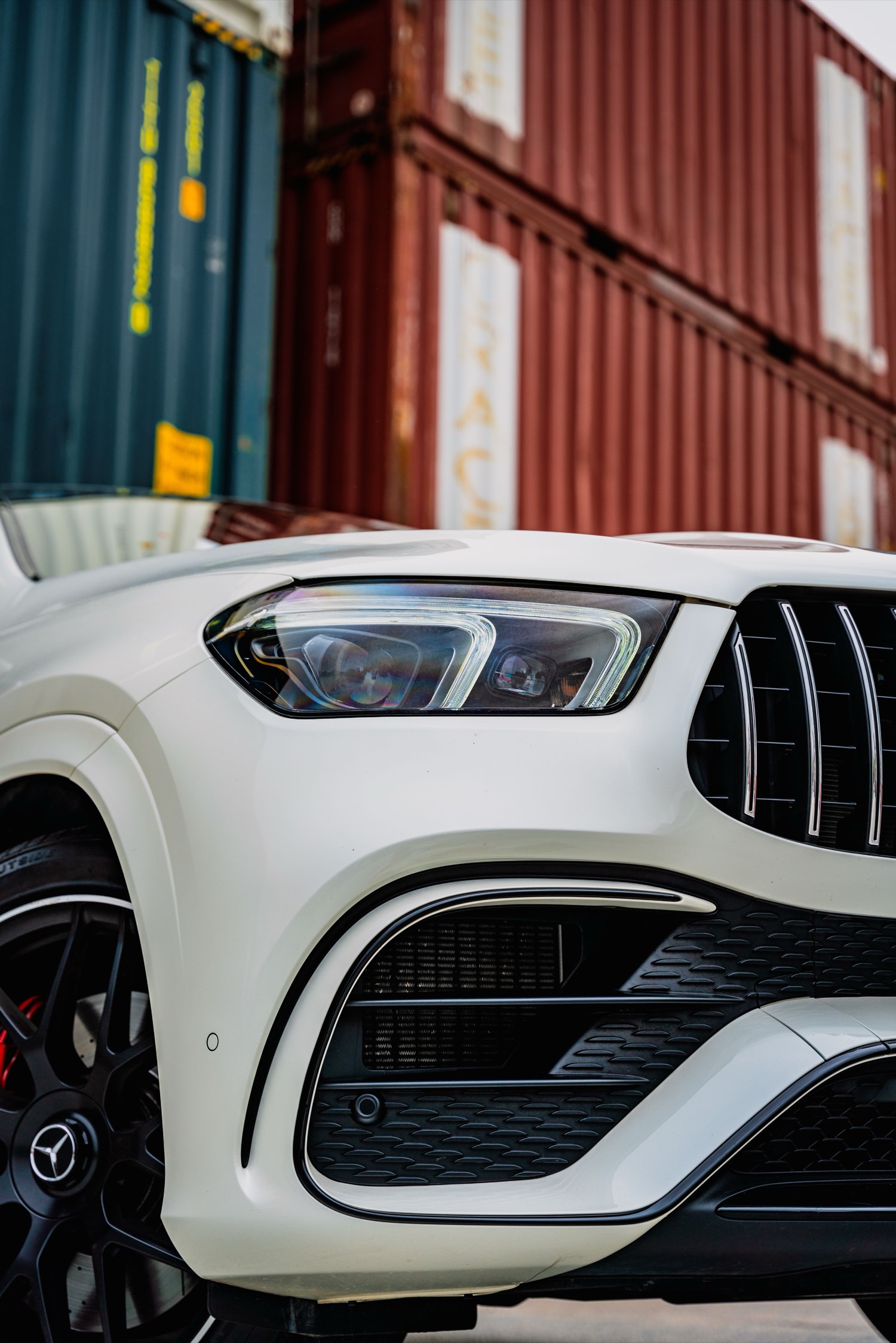A vehicle waiting in front of stacked shipping containers